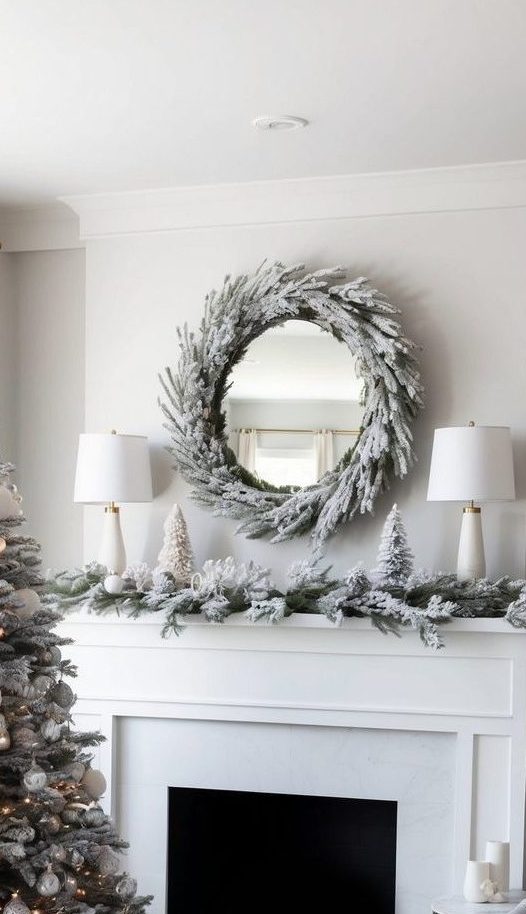 A frosted wreath and garland on top of a white mantel beside two lamps